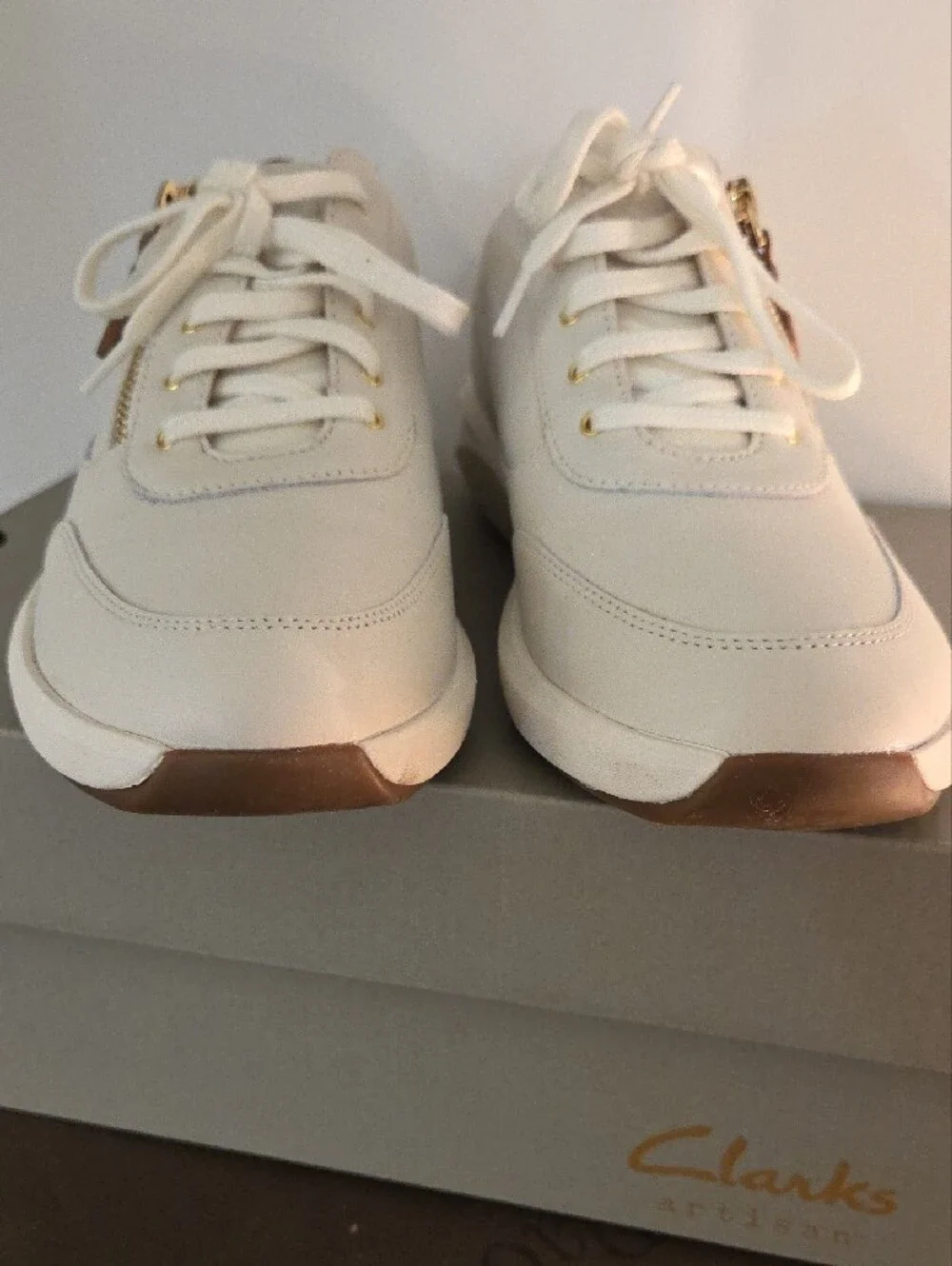 Clarks Cream Leather Sneakers with Brown Heel Accent and Gold Zip